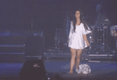 a woman in a white dress is standing on a stage in front of a band .