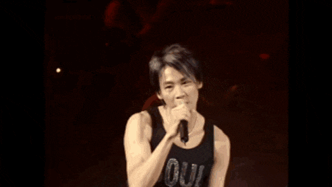 a man singing into a microphone while wearing a soul tank top