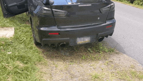 a black car is parked on the side of the road and has a license plate that says ' nc ' on it