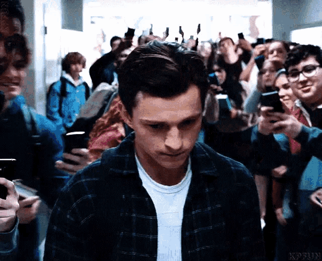 a man in a plaid shirt is surrounded by people holding their cell phones