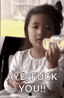 a little girl is holding a bottle and saying `` aye , fuck you '' .