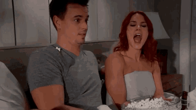 a man and a woman are eating popcorn together