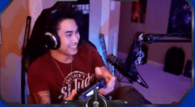 a man wearing headphones is sitting in a chair holding a video game controller and smiling .