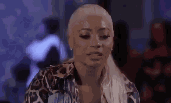 a woman in a leopard print shirt is sitting at a table in a dark room .