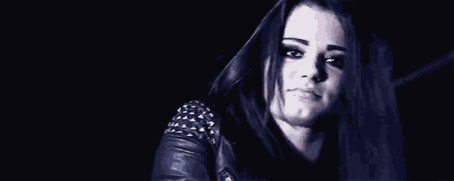 the woman is wearing a leather jacket with studs on the shoulder .