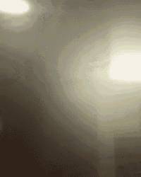 a blurred image of a person standing in a dark room with a light shining through the smoke .