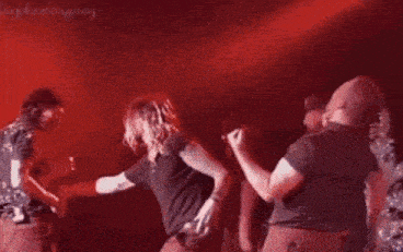 a group of people are dancing on stage in front of a red light .
