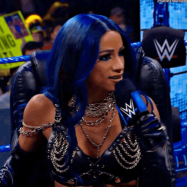 a woman with blue hair is sitting in a chair with a microphone in front of her .