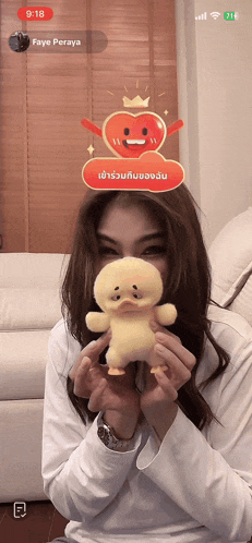 a woman holding a stuffed duck in front of a screen that says faye peraya on it