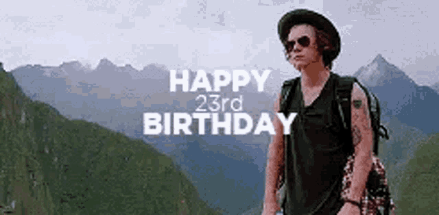 a man wearing a hat and sunglasses is standing in front of a mountain with the words `` happy 23rd birthday '' .