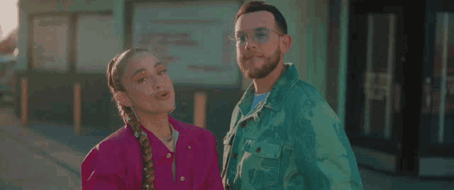 a man and a woman are standing next to each other on a street