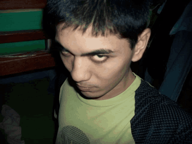 a close up of a man 's face with a green shirt on