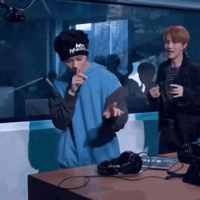 two men are standing next to each other in front of a microphone in a studio .