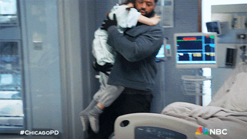a man is holding a child in his arms in a hospital room with a nbc logo in the corner