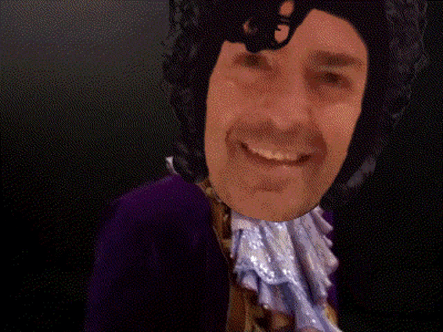 a man in a purple suit is smiling and holding a pie
