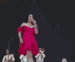 a woman in a red dress is standing on a stage with a microphone .