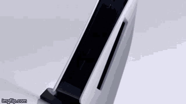 a playstation 5 is sitting on top of a charger on a white surface .