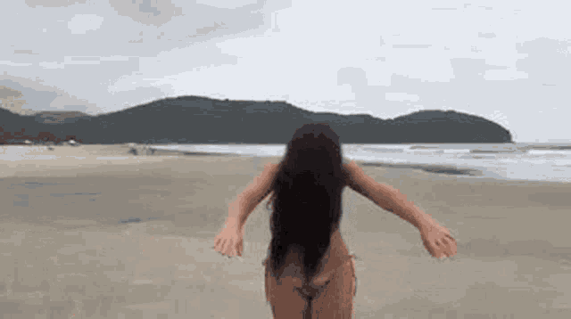 a woman in a bikini is standing on a beach .