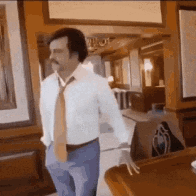 a man in a white shirt and tie is walking in a room