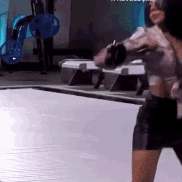 a woman is standing on a trampoline in a gym .