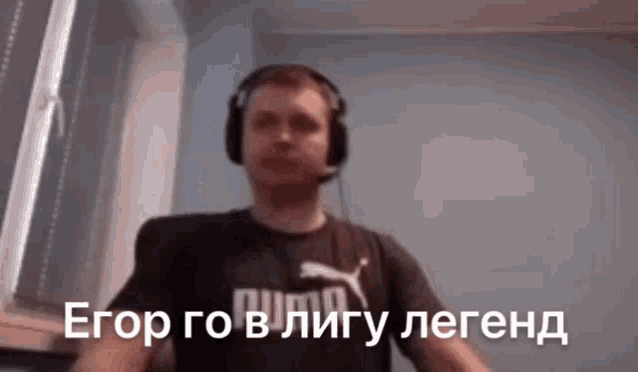 a man wearing headphones and a puma shirt is standing in front of a window