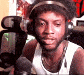 a man wearing headphones and a tank top is talking into a microphone .