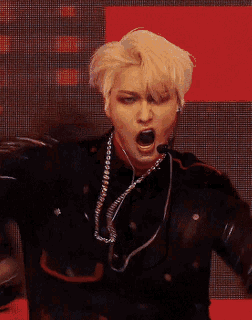 a man with blonde hair is wearing a necklace and earphones