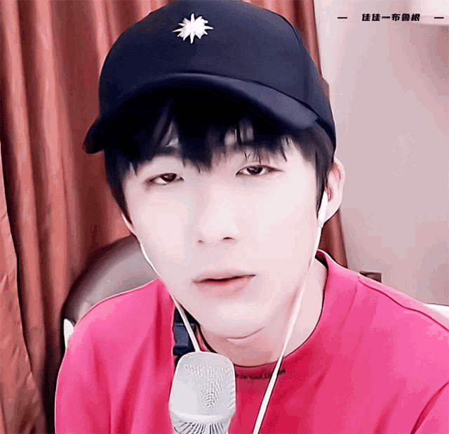 a young man wearing a hat and a pink shirt is looking at the camera