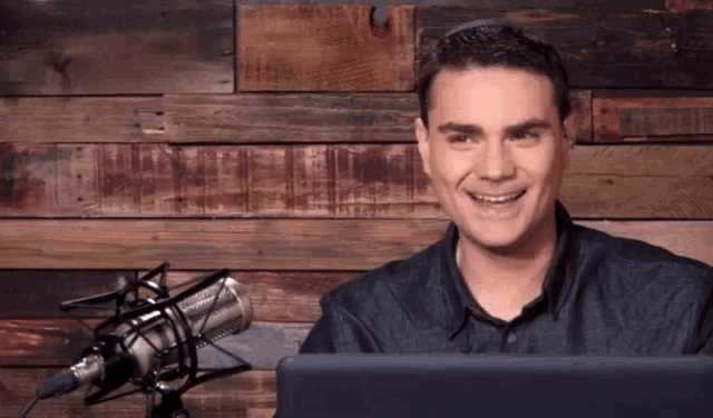 a man is smiling in front of a microphone