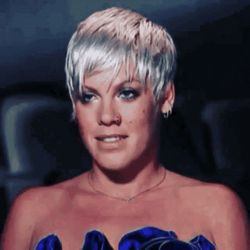 a woman with short blonde hair is wearing a blue dress and a necklace .