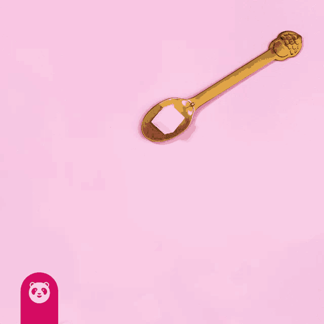 a gold spoon with sugar cubes on a pink background