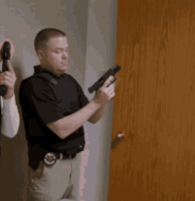a man holding a gun with a badge on his belt