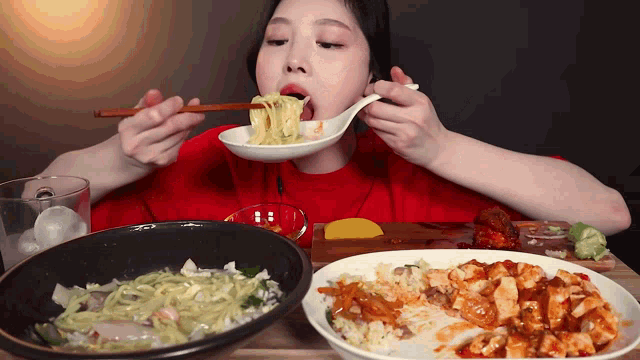 a woman is eating noodles with chopsticks from a spoon