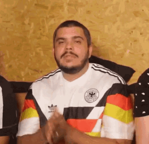 a man with a beard is wearing a german flag shirt and clapping .