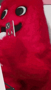 a red stuffed animal is holding a cell phone .