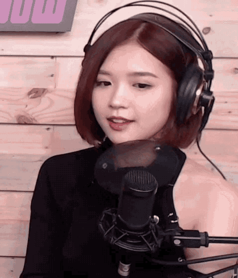 a woman wearing headphones is standing in front of a microphone
