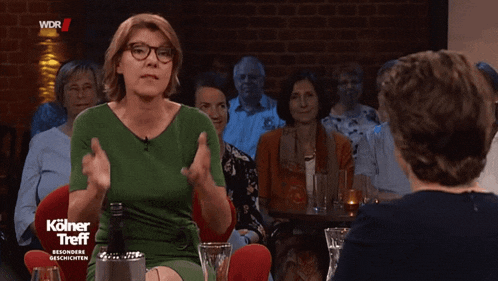 a woman in a green dress talks to another woman on a television show called kolner treff besondere geschichten