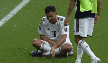a soccer player with the number 18 on his shirt is sitting on the ground