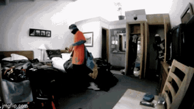 a man in an orange shirt is standing in a messy room with imgflip.com written on the bottom