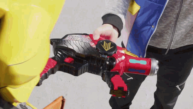 a person is holding a red toy with a yellow arrow pointing up