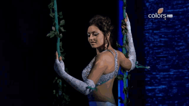 a woman in a yellow dress is dancing on a stage with a man in a silver suit behind her