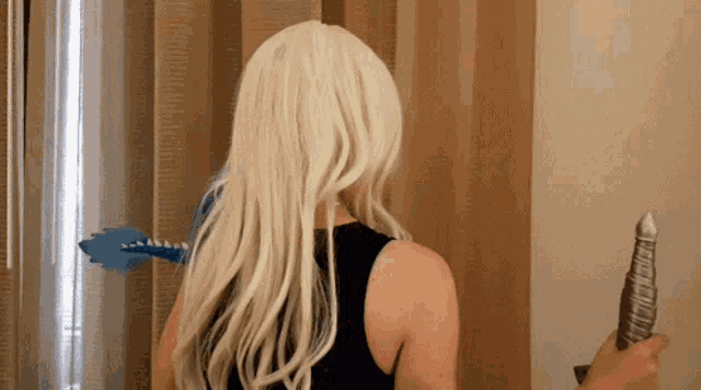 a woman with long blonde hair is standing in front of a curtain
