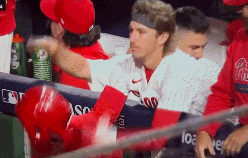 a man in a phillies jersey is talking to another man