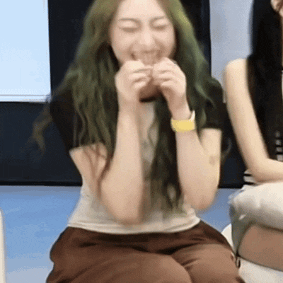 a woman with green hair is sitting with her eyes closed and her mouth open