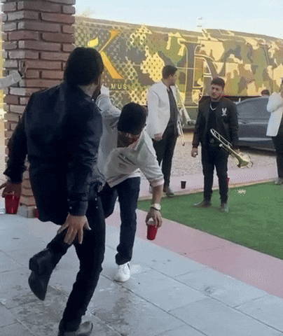 a group of men are dancing in front of a building that says music on it