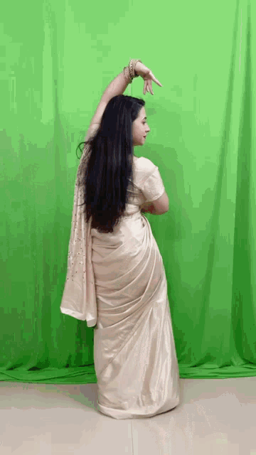 a woman in a white dress is dancing in front of a green screen