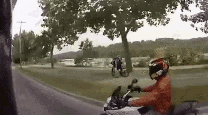a man is riding a motorcycle down a road while another man is riding a bike .