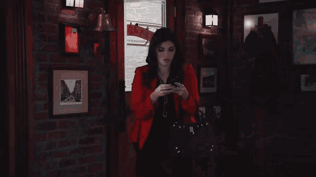 a woman in a red jacket is sitting in a dark room