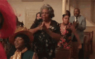 a group of people are sitting at a table in a church clapping .