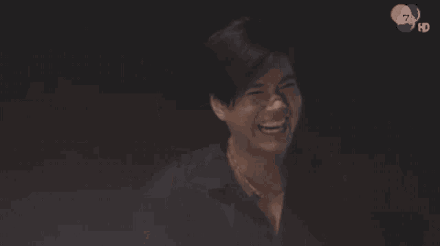 a man in a black shirt is laughing in the dark .